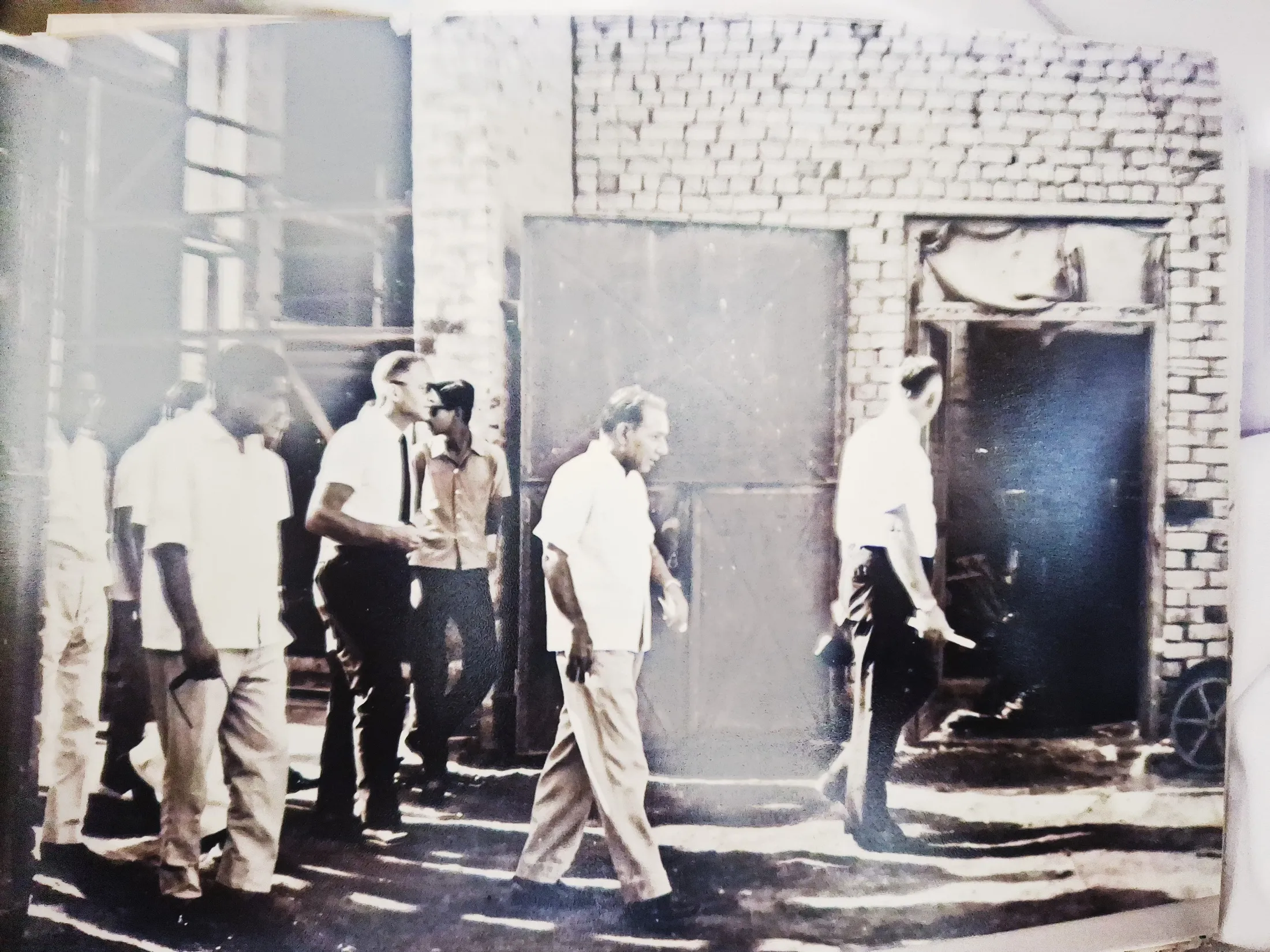 Visitors and staff walk the mill yard past the brick shelling house.
