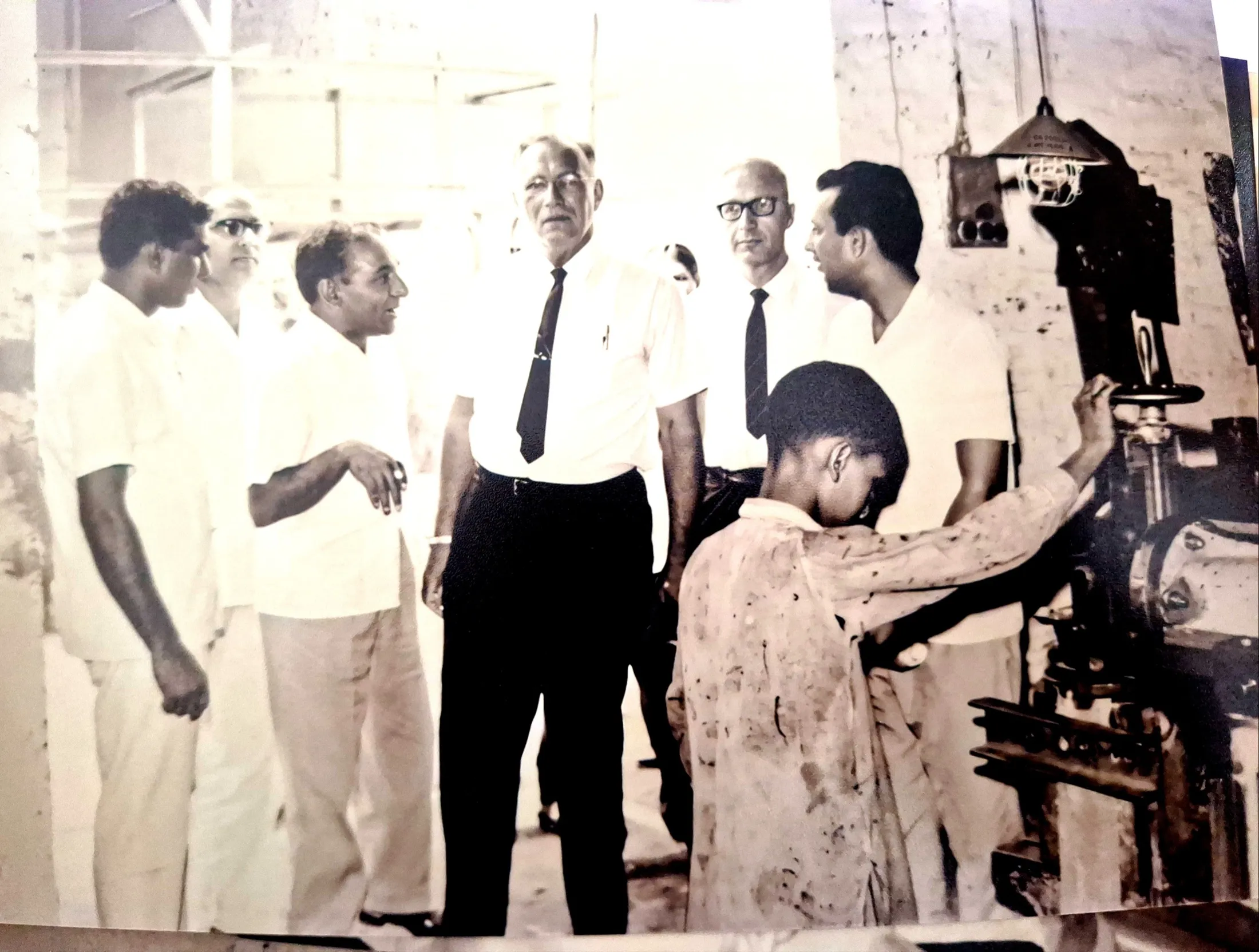 A young mill hand turns a valve wheel as the founder and visitors look on.